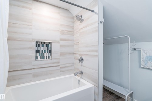 Bathtub and shower combination featuring large format neutral-toned wall tiles with a recessed niche accented by mosaic tiling - 10934 80 Avenue Nw, Edmonton, AB - Indoor Photo Showing Bathroom