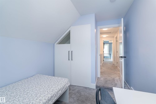 Attic room featuring a built-in wardrobe with black handles and an angled upper window - 10934 80 Avenue Nw, Edmonton, AB - Indoor Photo Showing Bedroom