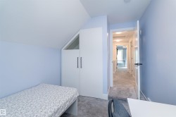 Attic room featuring a built-in wardrobe with black handles and an angled upper window - 