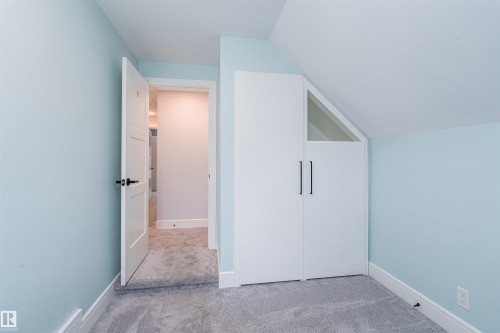 Room featuring light blue walls, gray carpet, white trim, and a built-in closet with white doors and black hardware - 10934 80 Avenue Nw, Edmonton, AB - Indoor Photo Showing Other Room