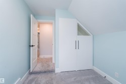 Room featuring light blue walls, gray carpet, white trim, and a built-in closet with white doors and black hardware - 