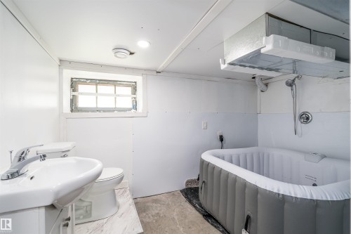 Bathroom featuring a pedestal sink, toilet, and an inflatable spa tub - 10934 80 Avenue Nw, Edmonton, AB - Indoor Photo Showing Bathroom
