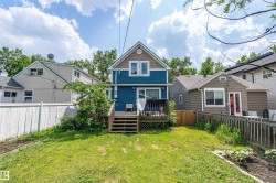 Expansive backyard featuring a manicured lawn, a wooden deck, and a privacy fence - 