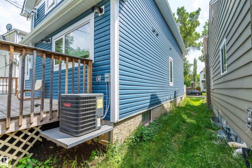 Rear exterior featuring blue vinyl siding, an elevated wood deck, and a lattice-skirted foundation - 10934 80 Avenue Nw, Edmonton, AB - Outdoor