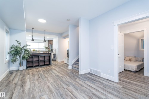 Open concept living space featuring wood-finish flooring, a kitchen with a built-in island, dual pendant lighting, and a skylight - 10934 80 Avenue Nw, Edmonton, AB - Indoor Photo Showing Living Room