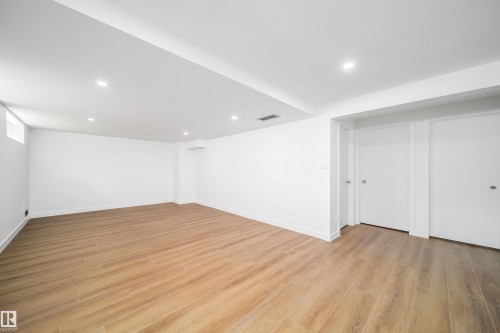 Spacious room showcasing warm wood-finish flooring throughout, recessed ceiling lighting, and clean white walls - #A 12 Invermere Pl, St. Albert, AB - Indoor Photo Showing Other Room