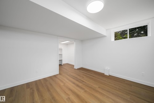 Wood-finish flooring, white walls, and a flush-mount ceiling light - #A 12 Invermere Pl, St. Albert, AB - Indoor Photo Showing Other Room