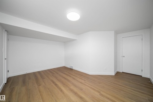 Wood-finish flooring with white baseboards, recessed ceiling beam, and a flush mount ceiling light fixture - #A 12 Invermere Pl, St. Albert, AB - Indoor Photo Showing Other Room