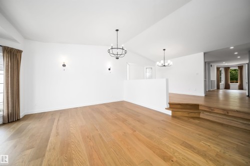 Vaulted ceiling, wood-finish flooring, two decorative sconces, and two chandeliers - #A 12 Invermere Pl, St. Albert, AB - Indoor Photo Showing Other Room