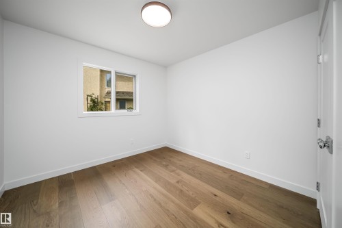 Wood-finish flooring, white painted walls, single window with white trim, flush mount ceiling light, white door with chrome hardware - #A 12 Invermere Pl, St. Albert, AB - Indoor Photo Showing Other Room