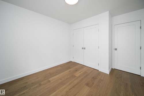 Wood-finish flooring with white walls, two panel doors, and a ceiling-mounted light fixture - #A 12 Invermere Pl, St. Albert, AB - Indoor Photo Showing Other Room