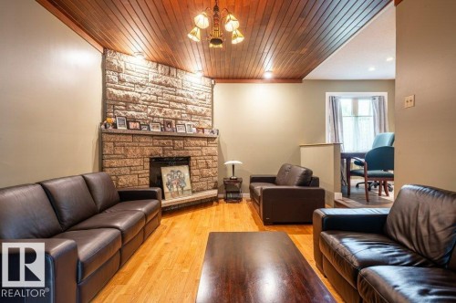 Family room with a prominent stone fireplace featuring a hearth and mantel - 14514 101 Avenue Nw, Edmonton, AB - Indoor Photo Showing Living Room With Fireplace