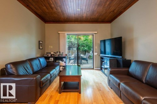 Family room area featuring wood-finish flooring, a wood plank ceiling, and direct access to an outdoor deck through sliding glass doors - 14514 101 Avenue Nw, Edmonton, AB - Indoor Photo Showing Living Room