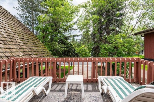 Rooftop deck featuring a wood-shingle roof, wood railing, and surrounding mature trees - 14514 101 Avenue Nw, Edmonton, AB - Outdoor With Deck Patio Veranda