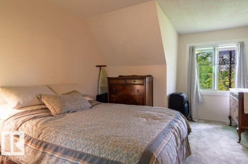 Carpeted room featuring a sloped ceiling and a window with white trim - 14514 101 Avenue Nw, Edmonton, AB - Indoor Photo Showing Bedroom