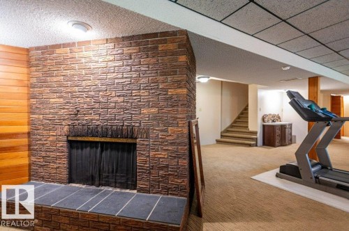 Stone-clad fireplace featuring an elevated hearth with dark tile surfacing - 14514 101 Avenue Nw, Edmonton, AB - Indoor With Fireplace