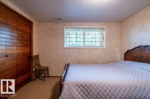 Interior room featuring wood-finish bi-fold closet doors and a single window with blinds - 14514 101 Avenue Nw, Edmonton, AB - Indoor Photo Showing Bedroom