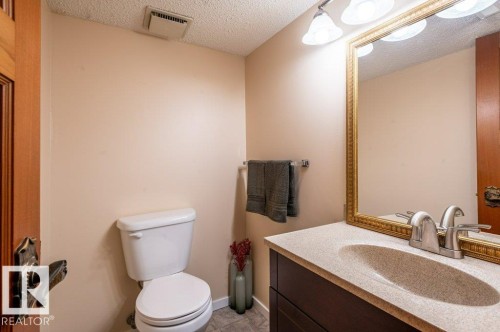 Bathroom featuring a dark wood-finish vanity with an integrated sink, a gold-framed mirror, and a four-light vanity fixture - 14514 101 Avenue Nw, Edmonton, AB - Indoor Photo Showing Bathroom