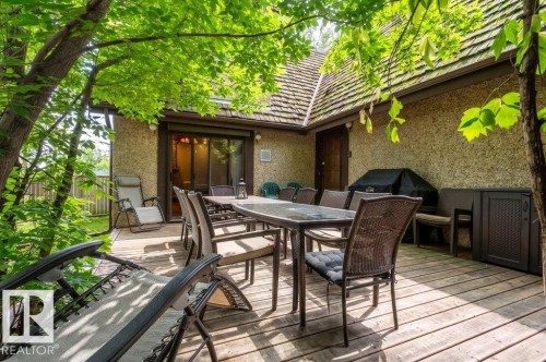 Outdoor wood-finish deck with mature tree canopy, textured stucco exterior, and a sliding glass door entry - 14514 101 Avenue Nw, Edmonton, AB - Outdoor With Deck Patio Veranda With Exterior