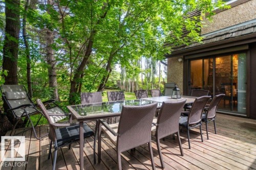 Expansive wood-finish deck with mature trees, offering direct access to the interior via sliding glass doors - 14514 101 Avenue Nw, Edmonton, AB - Outdoor With Deck Patio Veranda With Exterior