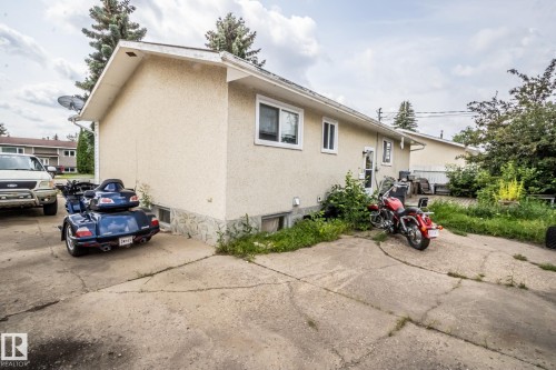 Exterior building with stucco finish, stone veneer foundation, white-framed windows, and concrete driveway - 4322 49 Ave, St. Paul Town, AB - Outdoor With Exterior