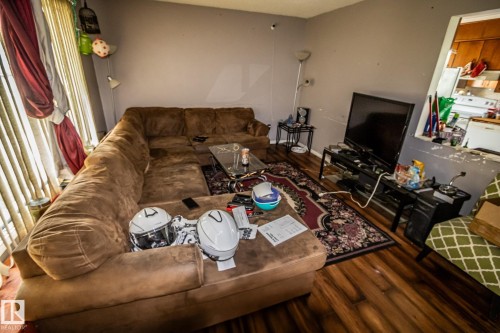 Wood-finish flooring, neutral wall paint, and a pass-through window to the kitchen - 4322 49 Ave, St. Paul Town, AB - Indoor Photo Showing Living Room