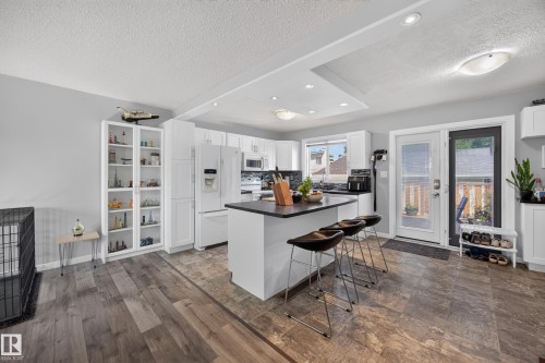 Kitchen featuring a center island with bar seating, white cabinetry, dark countertops, and stainless steel appliances - 156 Clareview Road Nw, Edmonton, AB - Indoor