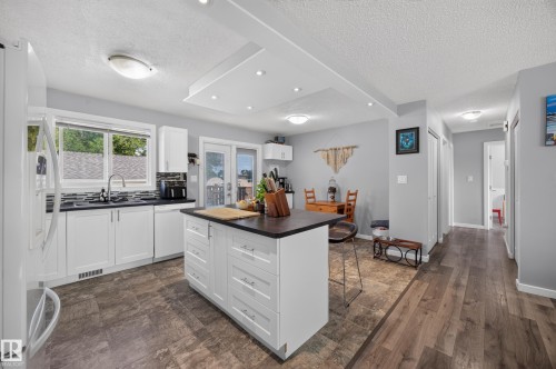 Modern kitchen featuring white cabinetry with a large center island, wood-finish flooring throughout, stainless steel appliances, and abundant natural light from multi-pane windows - 156 Clareview Road Nw, Edmonton, AB - Indoor Photo Showing Kitchen