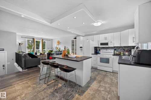 Kitchen featuring white cabinetry, dark countertops, a tile backsplash, and a central island with integrated seating - 156 Clareview Road Nw, Edmonton, AB - Indoor Photo Showing Kitchen