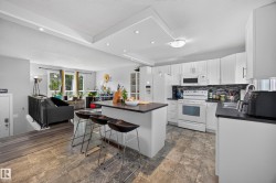 Kitchen featuring white cabinetry, dark countertops, a tile backsplash, and a central island with integrated seating - 