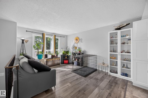 Bright, open living space featuring wood-finish flooring, a charcoal upholstered sofa, and expansive built-in shelving with display storage - 156 Clareview Road Nw, Edmonton, AB - Indoor Photo Showing Living Room