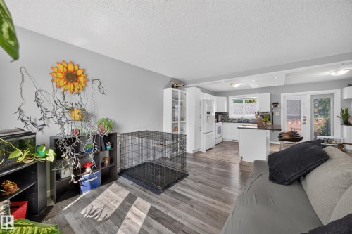 Open-concept living space featuring wood-finish flooring, recessed lighting, and a kitchen with white cabinetry and a patio door - 156 Clareview Road Nw, Edmonton, AB - Indoor