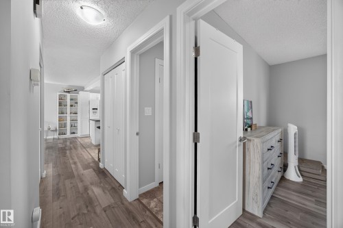 Wood-finish flooring throughout, white interior doors, and a flush-mount ceiling light fixture - 156 Clareview Road Nw, Edmonton, AB - Indoor Photo Showing Other Room
