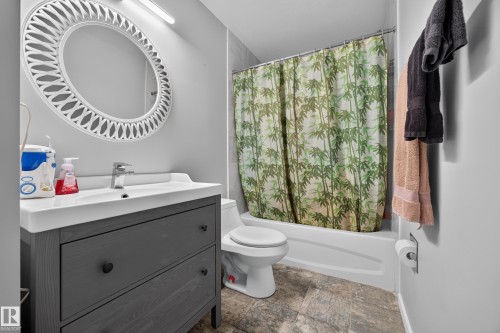 Modern bathroom featuring a charcoal gray vanity with white quartz countertop and integrated sink, chrome wall-mounted faucet, and circular illuminated mirror - 156 Clareview Road Nw, Edmonton, AB - Indoor Photo Showing Bathroom