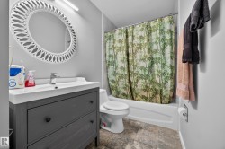Modern bathroom featuring a charcoal gray vanity with white quartz countertop and integrated sink, chrome wall-mounted faucet, and circular illuminated mirror - 
