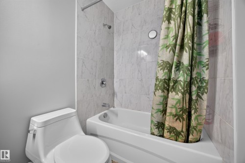 White ceramic toilet and bathtub with a tiled shower surround featuring a chrome shower head and faucet - 156 Clareview Road Nw, Edmonton, AB - Indoor Photo Showing Bathroom