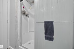 Shower enclosure featuring a built-in shelf, marble-look tile, and a textured privacy glass panel - 