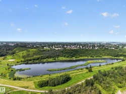 Expansive natural landscape featuring a serene lake, surrounding green spaces, and mature trees - 