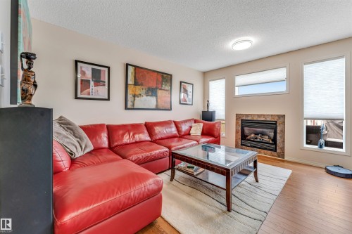 Wood-finish flooring throughout, featuring a fireplace with a tiled surround - 3032 31 Avenue Nw, Edmonton, AB - Indoor Photo Showing Living Room With Fireplace