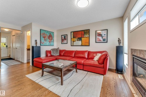 Hardwood-style flooring throughout, integrated fireplace with tile surround, and multiple windows providing natural light - 3032 31 Avenue Nw, Edmonton, AB - Indoor Photo Showing Living Room With Fireplace