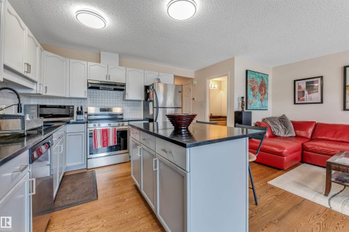 Kitchen featuring stainless steel appliances, dark countertops, white cabinetry, and a patterned backsplash - 3032 31 Avenue Nw, Edmonton, AB - Indoor Photo Showing Kitchen