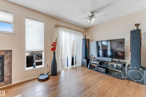 Hardwood-finish flooring, built-in fireplace with tile surround, large windows with blinds, sliding glass patio door, and ceiling fan with lighting - 3032 31 Avenue Nw, Edmonton, AB - Indoor Photo Showing Living Room With Fireplace