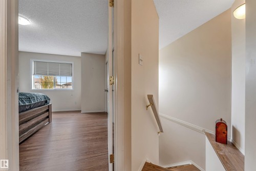 Wood-finish flooring throughout, window with blinds, and staircase with wood handrail - 3032 31 Avenue Nw, Edmonton, AB - Indoor Photo Showing Other Room