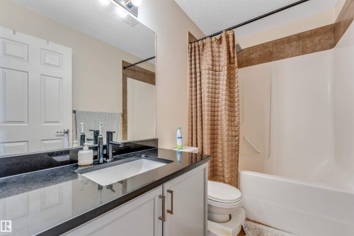 Vanity with black countertop, integrated rectangular sink, and matte black faucet - 3032 31 Avenue Nw, Edmonton, AB - Indoor Photo Showing Bathroom