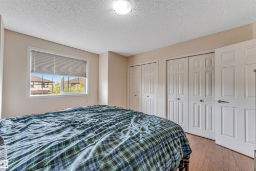 Recessed window with horizontal blinds, wood-finish flooring, and white paneled closet doors - 3032 31 Avenue Nw, Edmonton, AB - Indoor Photo Showing Bedroom