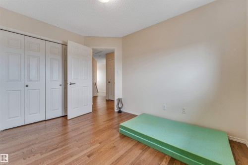 Wood-finish flooring throughout, white bi-fold closet doors, and light-toned wall paint - 3032 31 Avenue Nw, Edmonton, AB - Indoor Photo Showing Other Room