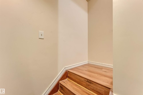 Wood-finish flooring on staircase with white trim - 3032 31 Avenue Nw, Edmonton, AB - Indoor Photo Showing Other Room