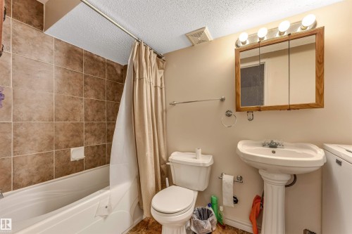 Pedestal sink, wall-mounted medicine cabinet with integrated lighting, tiled shower surround, and a built-in bathtub - 3032 31 Avenue Nw, Edmonton, AB - Indoor Photo Showing Bathroom