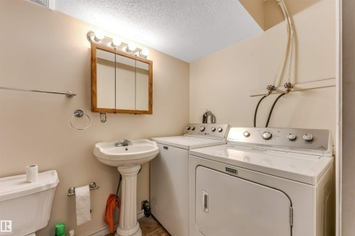 Pedestal sink, wall-mounted medicine cabinet, overhead vanity lighting, and ceramic tile flooring - 3032 31 Avenue Nw, Edmonton, AB - Indoor Photo Showing Laundry Room