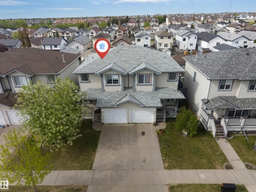 Duplex exterior featuring light-colored siding, a gray shingle roof, two attached garages, and a concrete driveway - 3032 31 Avenue Nw, Edmonton, AB - Outdoor With Facade